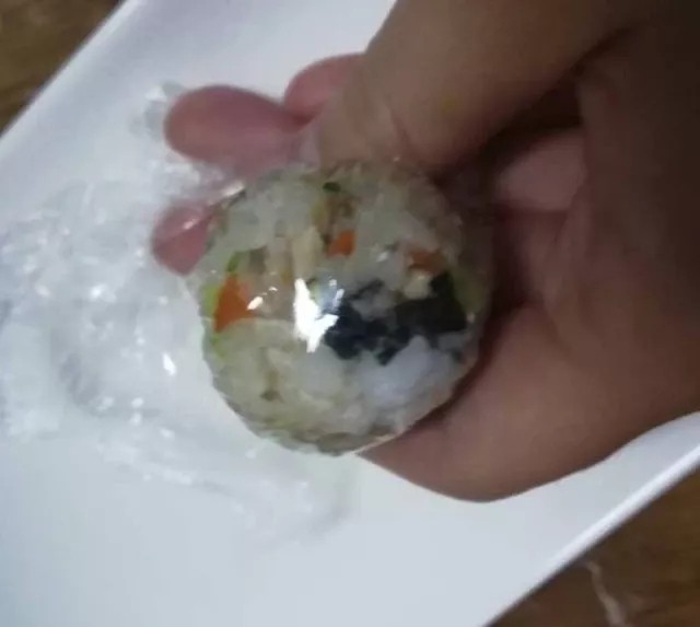 什锦饭团,晾至米饭不烫手,撕一点保鲜膜,取一小勺米饭,放在里保鲜膜揉圆。