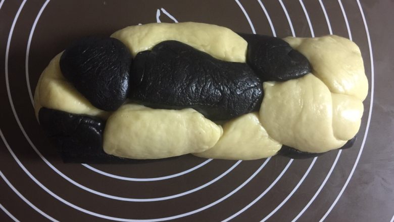 可爱的奶牛纹吐司(淡奶油版),松弛好后把两种颜色的面团间隔着随意摆放,团成一个圆柱体,可以稍微滚一滚,让它们更贴合。