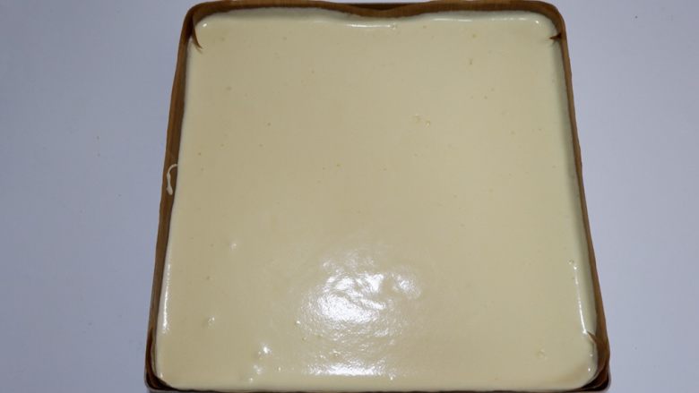 百变水果—草莓蛋糕卷,用手端起烤盘,让蛋糕糊流淌至平整,四个边角高低要一致。
在将烤盘轻震几下,震去大气泡