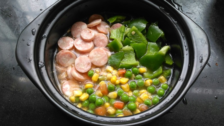 煲仔饭,香米泡好,把香肠,柿子椒,三色蔬菜粒摆放在米上