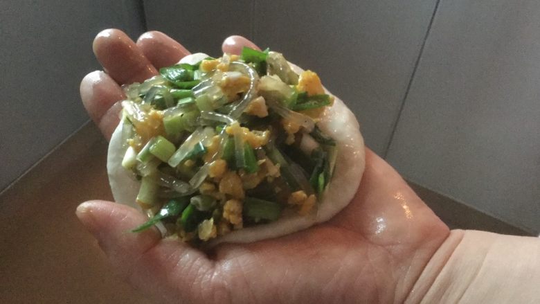 韭菜鸡蛋粉条馅饼,双手沾食用油,取出少许面团(面比较软,不用擀)双手拍、压,做成一张面皮,加入调好的馅,开始包
