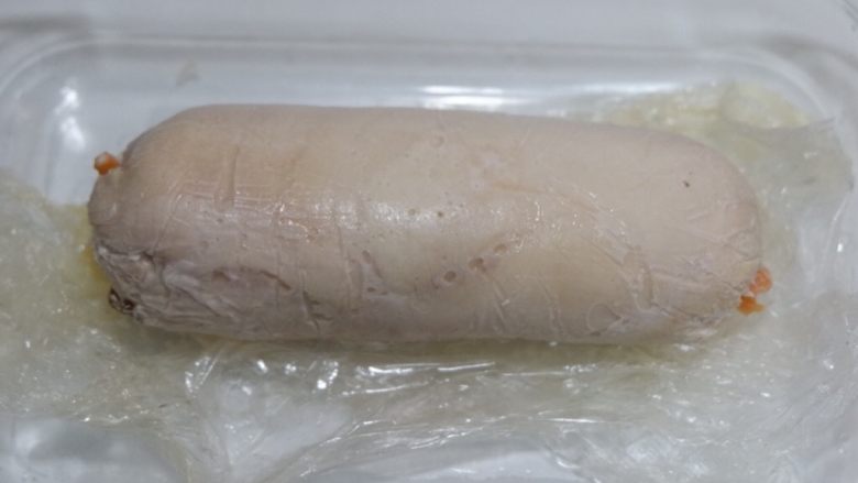 胡萝卜核桃鸡肉卷,蒸好的肉卷,拆开保鲜膜,将多余的汁液倒出,放置不烫手切开即可