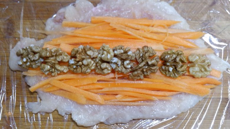 完美便当方程式「2」,底部铺一张保鲜膜,将鸡肉铺好,依次平铺上胡萝卜丝和<a style='color:red;display:inline-block;' href='/shicai/ 5056'>核桃仁</a>。