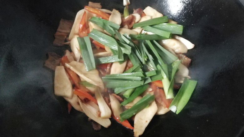 腊肉干锅鸡腿菇,再下入蒜青翻炒均匀;