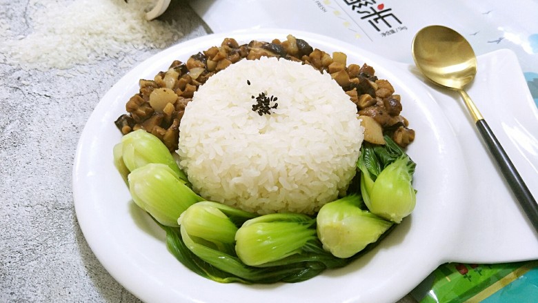 卤肉香菇饭,一碗米饭扣在盘子中间,把油菜和卤肉饭围在饭团周边。米饭上点缀一点黑芝麻就可以上桌了……