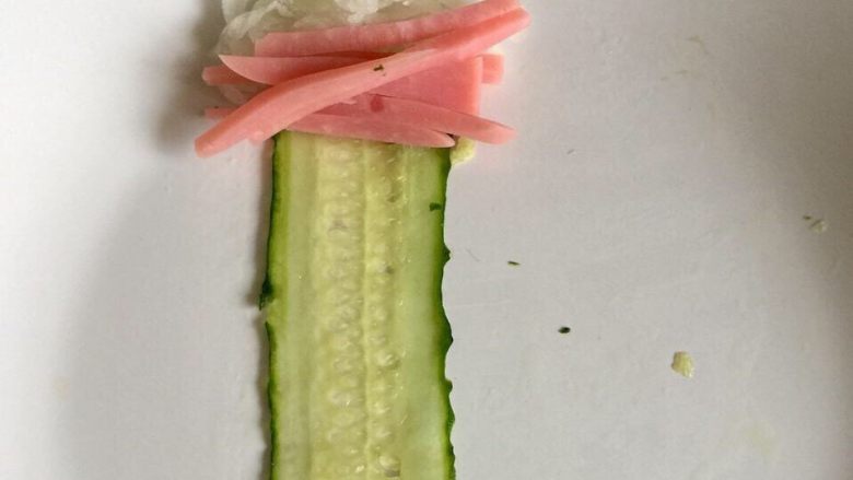给黄瓜换个吃法➕蒜蓉白萝卜火腿黄瓜卷,取一片黄瓜片,最上头放上少许白萝卜丝,火腿丝,然后将黄瓜片包裹它们卷起