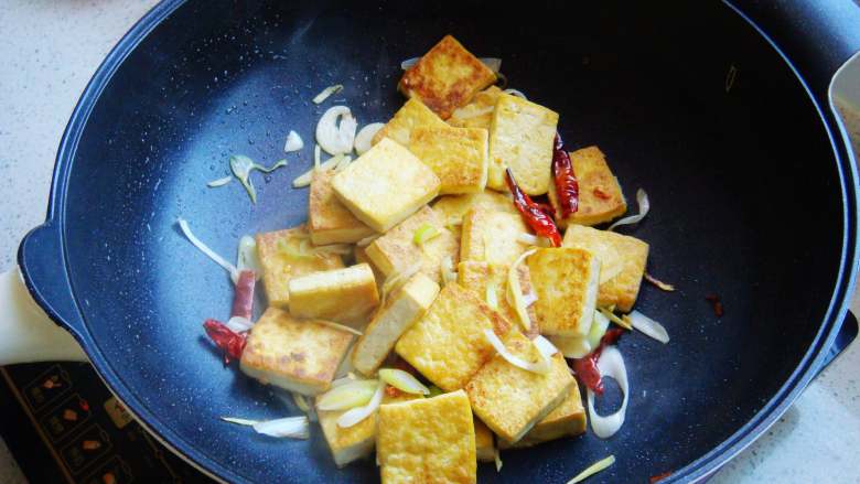 香煎家常豆腐,两面煎成金黄色,倒入葱段、辣椒、姜蒜翻炒均匀。