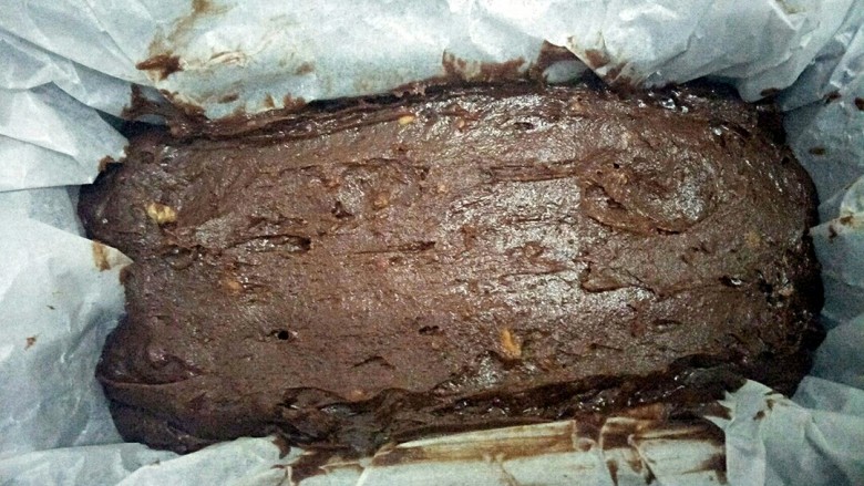布朗尼核桃仁蛋糕,六寸模具中垫上油纸,放入蛋糕糊,振动蛋糕糊让蛋糕糊铺平,并用刮刀刮平表面。