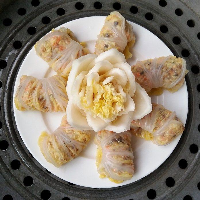 莲花娃娃菜&三鲜娃娃菜卷,将包好的菜卷收口朝下和剪好的菜帮一起放进盘中,在菜帮上稍微撒点盐,上锅隔水蒸20分钟,出锅后淋上香油,撒上火腿碎即可。
