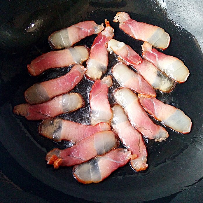 湘味萝卜干炒腊肉,锅中少量油烧7成热,放进切好的腊肉煸炒至肥肉的部分变得透明。