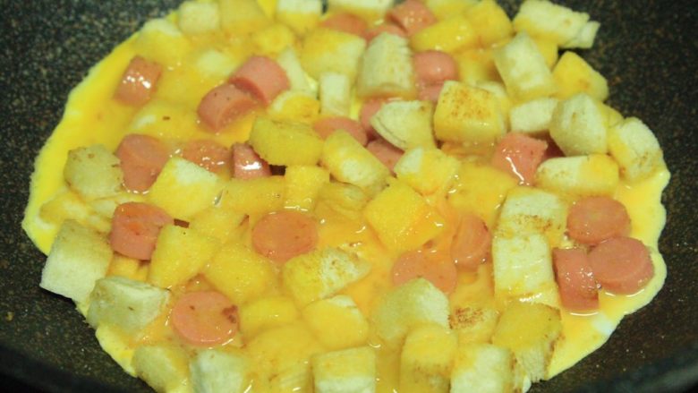 馒头火腿鸡蛋饼,待火腿丁煎至7分熟,将打散的蛋液倒入