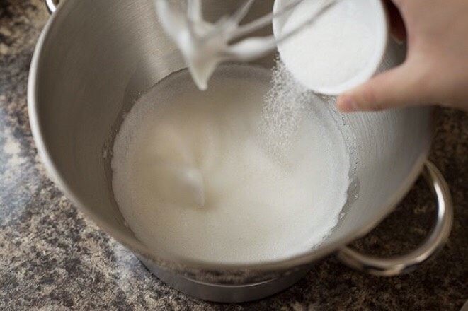 草莓奶油瑞士蛋糕卷,拿起盛有蛋白的盆,加入白醋几滴或者柠檬汁几滴,再加入10克白砂糖,用电动打蛋器低速打发至出现大的鱼眼泡,这时再加入10克白砂糖,用中速打发至鱼眼泡变成细小的泡,继续打发至湿性发泡,这时将剩下的白砂糖都倒入蛋白中,用高速打发至干性发泡。