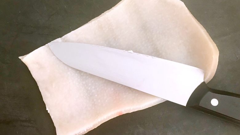 五香皮卷,把焯好猪皮捞出来,用刀刮去肉皮里面的油脂