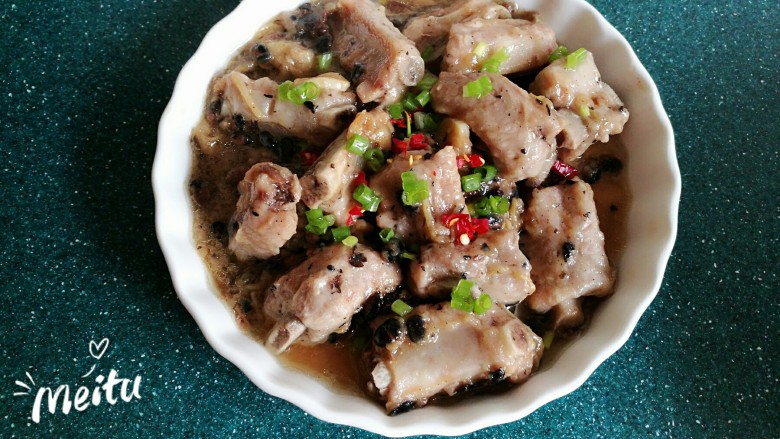 蒜香豆豉蒸排骨,将蒸好的排骨装盘,上面撒一点青红辣椒碎和小葱末。