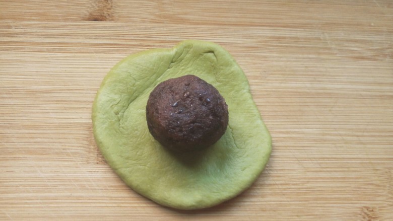 抹茶红豆包,取一小面团擀成圆形,包入豆沙馅。