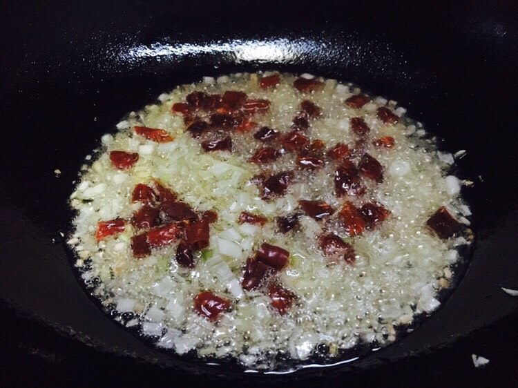 美味私房口蘑酱拌饭,锅热放入凉油,油要稍稍的多些,大约1大汤勺半左右,放入葱姜蒜和辣椒段爆香。