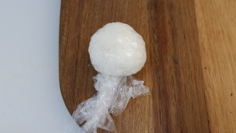 卡通大白饭团便当盒,用保鲜膜包裹住捏成圆形,捏好不要拆开保鲜膜,直接放到一旁定型备用