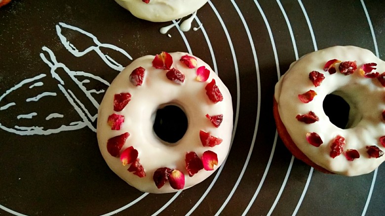 甜甜圈,在巧克力未干时，将蔓越莓和小玫瑰花瓣装饰在上面。