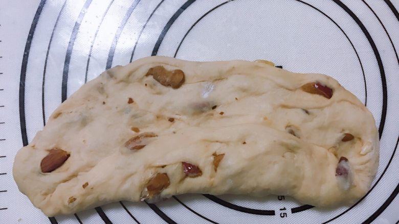 红糖红枣果仁软欧,
下面就要对面团进行整形,取一块面团。用擀面杖擀成牛舌状,将一边的1/2折叠;