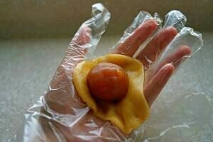 广式月饼,包馅。馅揉圆待用。皮在手中捏扁。放上馅料,用虎口小心的把面皮往上推,整理好收口,并搓圆。