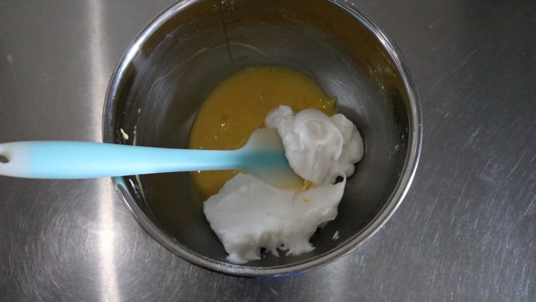 呆萌小可爱杯子蛋糕,取三分之一蛋白放入蛋黄糊中,快速2、8点翻拌均匀