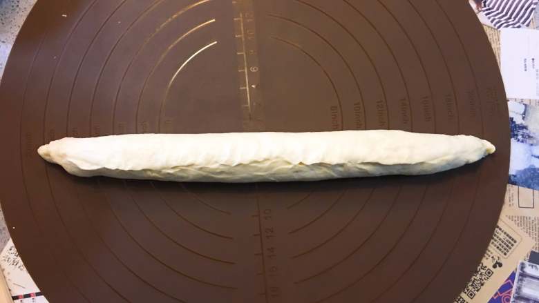 黃金椰蓉吐司,將麵片從一端捲起收口捏緊,並將兩頭也收口捏緊。