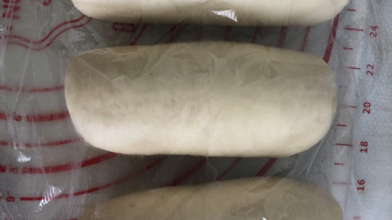 奶香葡萄干吐司,静置好擀开,卷起盖上保鲜膜再次静置15分钟