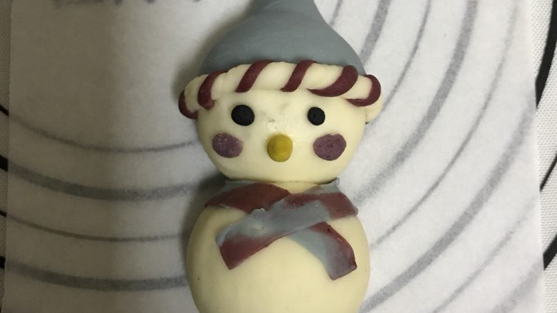 花式面点—圣诞雪人馒头,眼睛用竹炭粉来做成黑色,鼻子用南瓜粉,腮红可以用之前的红色面团