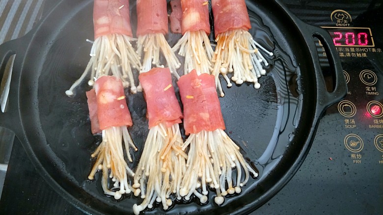 培根金针菇卷,放入培根金针菇卷小火慢煎，金针菇上再刷少许酱汁