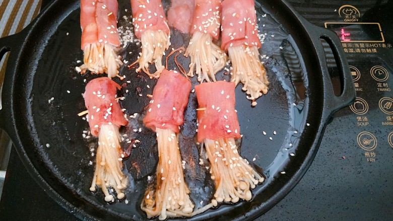 培根金针菇卷,翻面煎熟后，撒上适量芝麻