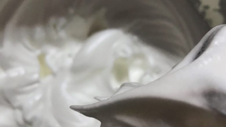 椰蓉紫薯蛋糕,蛋清打至出现鱼眼泡的时候,加入1/3细砂糖。打至泡沫细腻的时候再加入1/3细砂糖,打至出现有明显纹路的时候,加入剩余的1/3细砂糖。一直打到能拉出一个坚挺的小尖角。