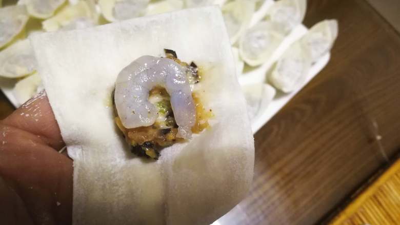虾仁元宝馄饨,虾仁的也同样的方法,先放少量的肉馅,再放虾仁。虾仁不是太大的直接放一整个,大的虾仁也可以切成两段方便包。