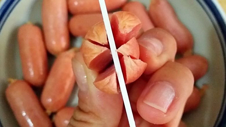 红香肠(非油炸)――快手复刻美味,在红香肠一端切三刀,等分成六瓣,切至香肠的三分之二处,在另一段留三分之一处横切一小口。