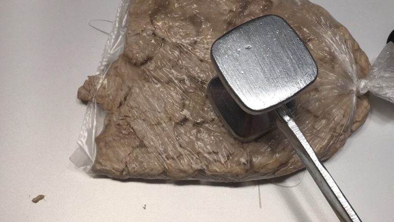 秘制肉松,压熟的猪肉块取出沥干水份放入保鲜膜中,用肉锤敲打,打散肉块。