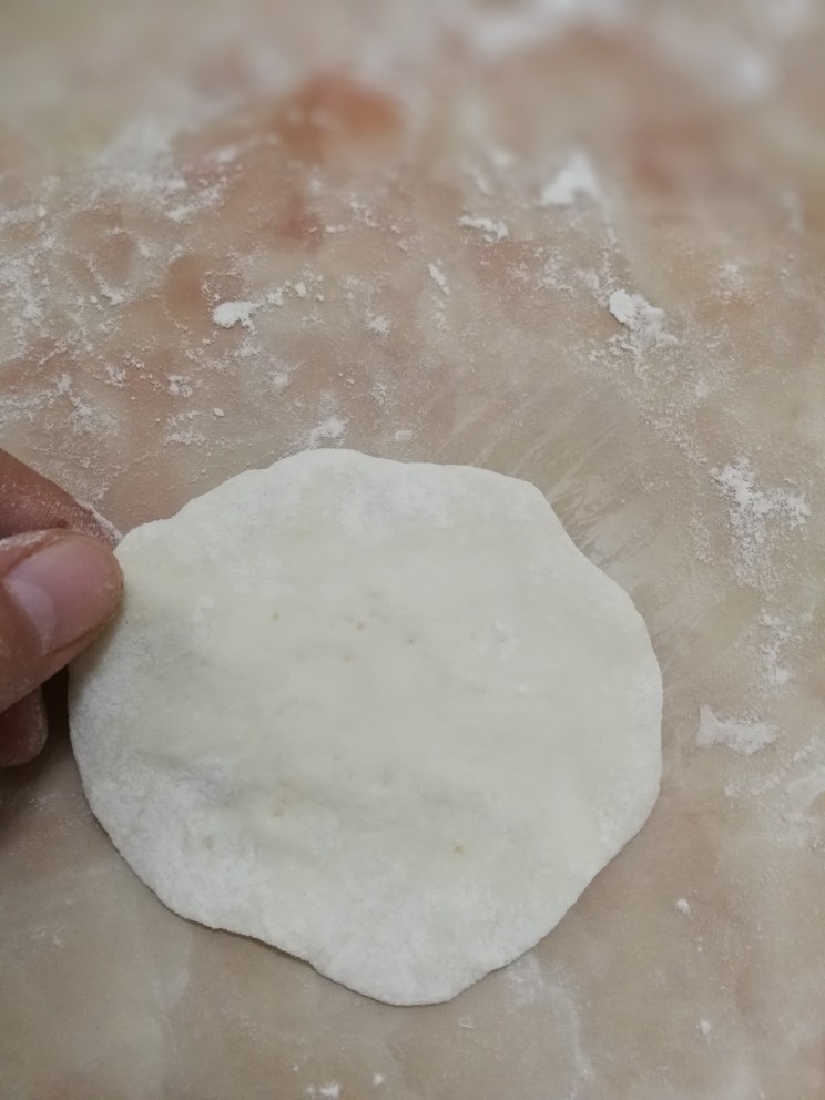 生煎小笼包,取其中一份,按扁成中间厚周围薄的包子皮(因为找不到擀面杖,所以我用手按的~)