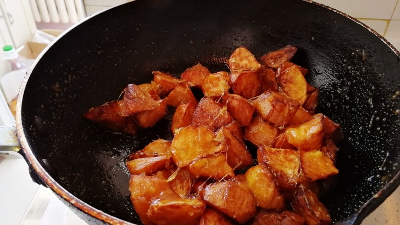 东北家常菜_地瓜挂浆,放入炸好的地瓜颠勺，不会颠勺的快速翻炒也可，使糖浆把地瓜包裹均匀。