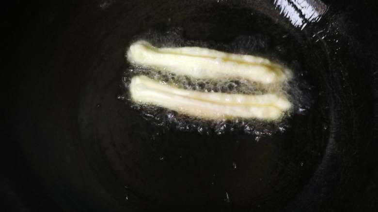 自制健康又美味的油条,锅里的油烧热,扔进去个小面团能马上浮起来,面团周围有很多气泡就可以放油条了,油太凉的话油条蓬松不起来。捏住油条胚的两头轻轻拉长放入油锅。