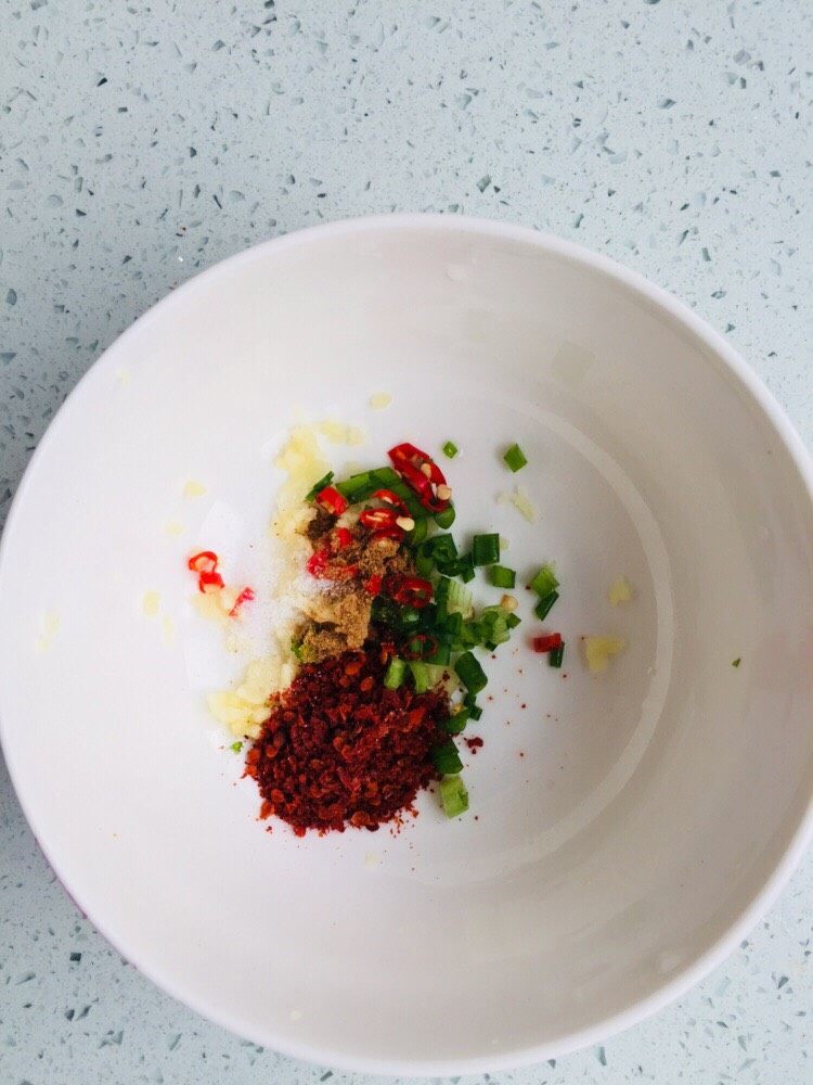 芹菜团子,在蒸制的过程中准备蘸水,将蒜捣成泥,细香葱、小米椒切碎加入辣椒面和少量的十三香