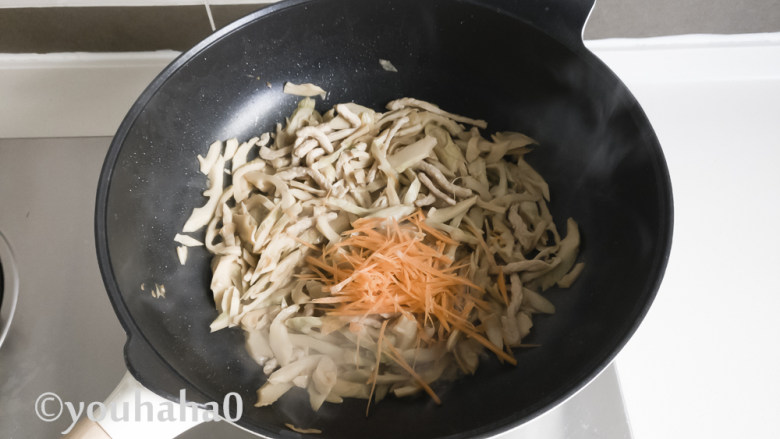 茶笋炒肉丝,笋丝比较干,翻炒的过程中要顺着锅边淋入少许的清水,最后放一点胡萝卜丝炒匀即可