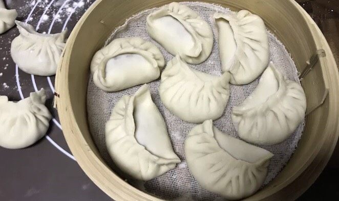 多汁牛肉蒸饺,蒸笼里垫好纱布,放上包好的蒸饺,盖上蒸笼盖子,放入蒸锅里。