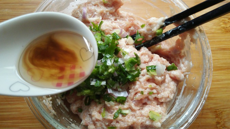 鸡蛋饺,浇一勺油在葱花上,然后把油搅拌均匀至葱花上。
