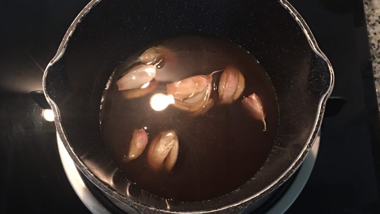 古早油葱粿,等待油葱粿放凉时,可烹煮酱汁。
蒜头洗净后拍扁连皮放入锅中,加入古早味油膏、糖、水煮滚,
