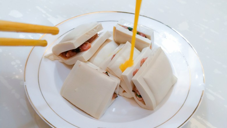 汤汁肉夹豆腐,将打好的蛋液淋在夹好肉的豆腐块上面,尽量淋在开口处。