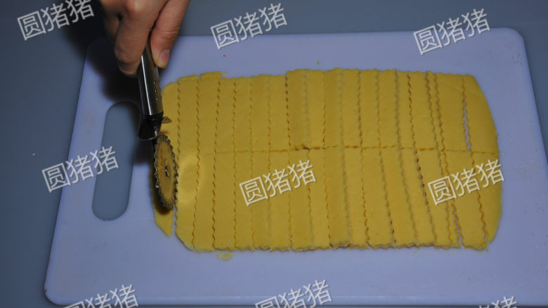 咸香芝士棒,用带齿的轮刀将面团切割成1CM宽,7CM长的条状。也可以用普通刀。