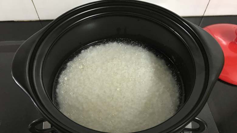 砂锅腊肠煲仔饭,加入过米半指甲的清水。然后再加入一勺油,搅匀。
