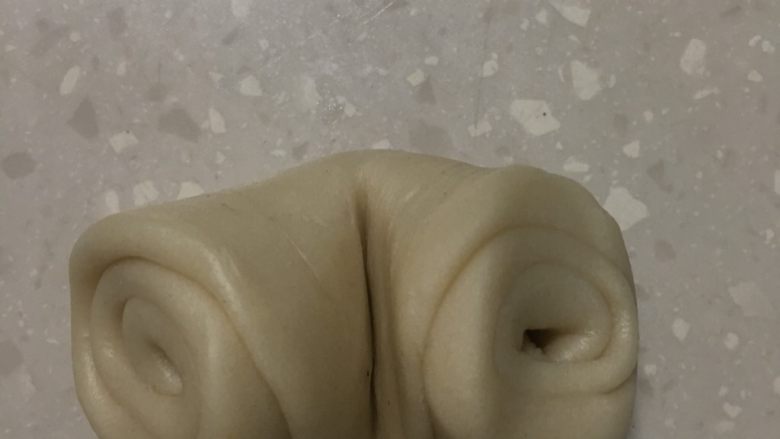 蛋黄酥,将油皮卷从两头捏向中间。