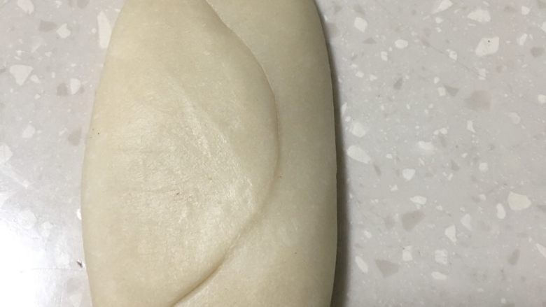 蛋黄酥,卷尾部朝上、再用手将卷压扁。