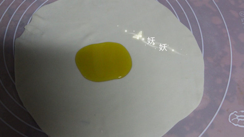 葱油烙饼,取其中的一个小剂子,擀成薄薄的片状,形状不规则也没用关系,尽量擀薄就可以了。面皮中间滴上植物油。