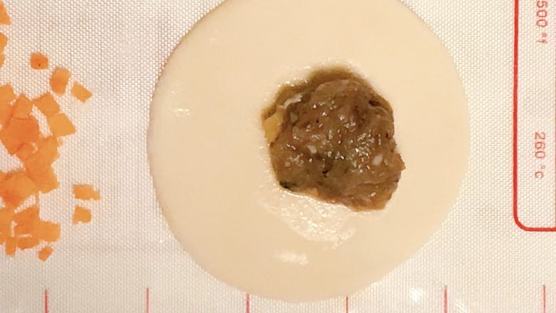年味の年年有“鱼”饺,取饺子皮,将牛肉馅放稍微靠边缘一点。饺子皮干的需要在四周蘸点水。
