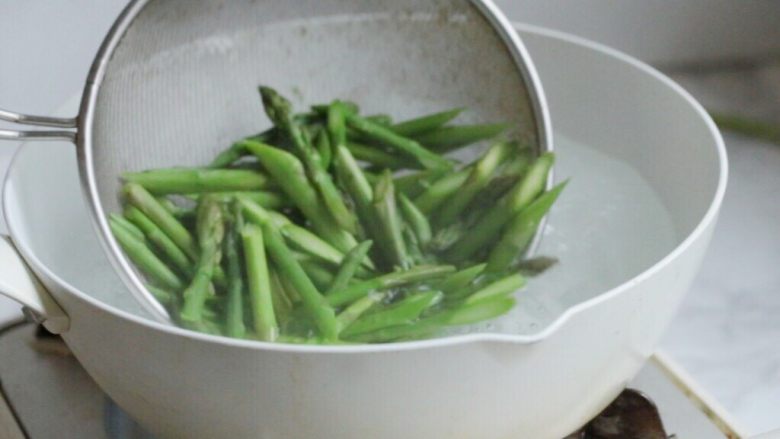 油淋芦笋,准备一锅清水,加入盐和油。水沸放入芦笋放入水中焯水2分钟。